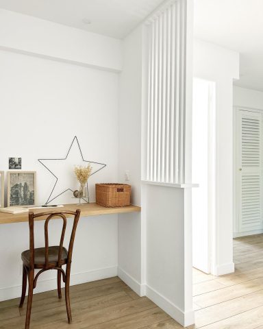 Espace de travail minimaliste avec une chaise, table en bois et décoration murale étoilée.