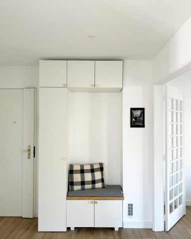 Espace d'entrée minimaliste avec banc, rangements blancs et décor sobre.