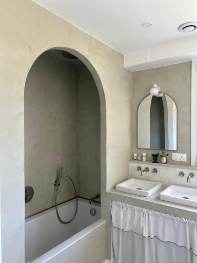 Salle de bain moderne avec baignoire encastrée et double vasque sous des miroirs.
